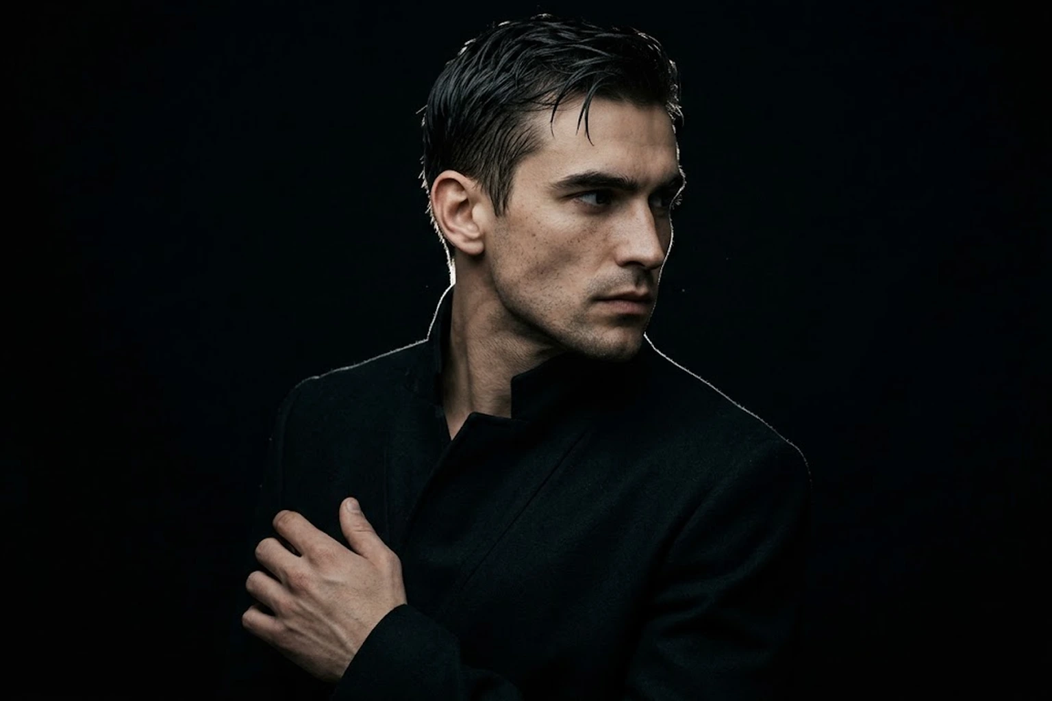 A man with folded arms against black